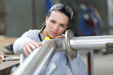 young female industrial engineer taking measures of metal pipeの写真素材
