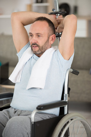 man in wheelchair rising dumbbells