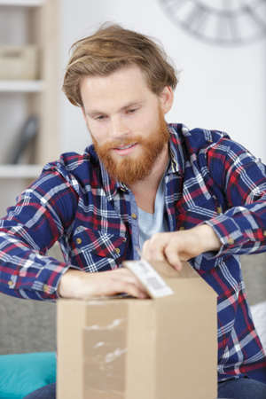 man at home opening a cardboard boxの写真素材