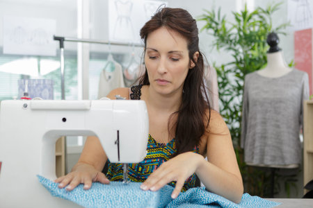 woman concentrating while using electric sewing machine