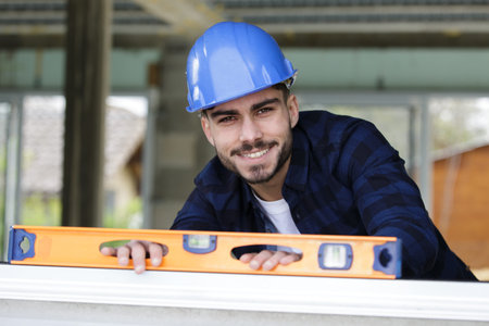 man using a spirit level to plumb a wall