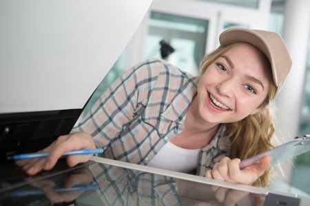 happy woman fixing a printer while smiling at the camera