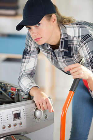 tired woman from carrying washer in kitchenの写真素材