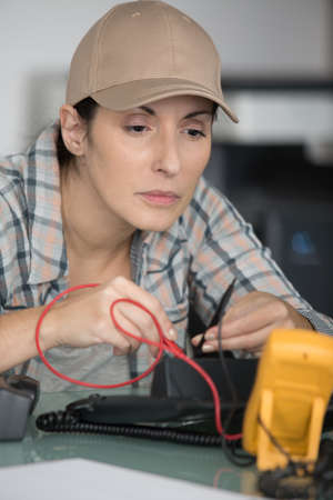 female electrician measures the voltage of a deviceの写真素材