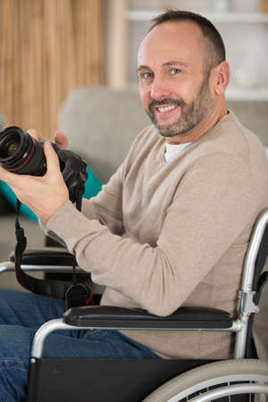 male photographer on wheelchair holding camera indoorの写真素材