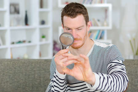man holding a magnifying glass and magnifying viewer ringの写真素材