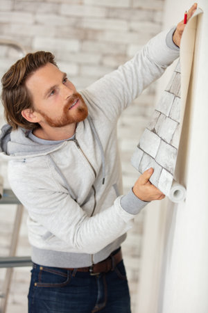 man holding wallpaper against a wall for visual effect