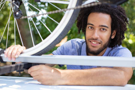 man holds his bike on the car roofの写真素材