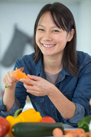 asian woman cooking vegetables in the kitchen in her apartmentの写真素材
