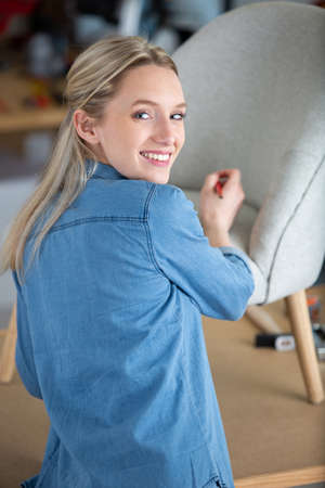 happy woman repairing chair indoorsの写真素材
