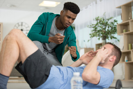 personal trainer encouraging mature man doing sit-ups