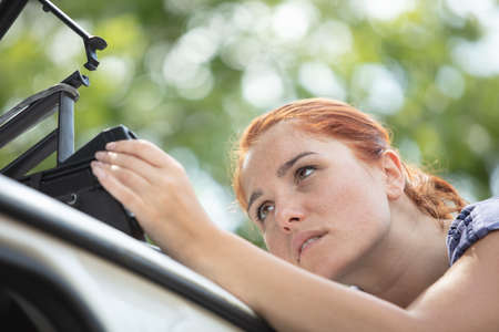woman puts things in the roof rack of the carの写真素材