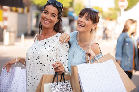 two happy friends shopping outdoorsの写真素材