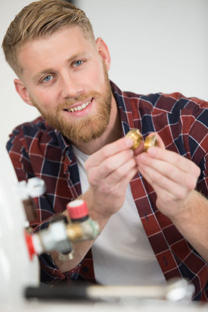 male plumber holding threaded fasteners for boiler
