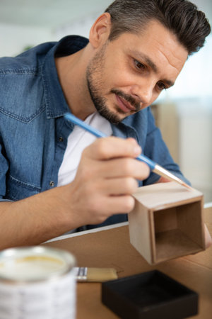 man paints a wooden box