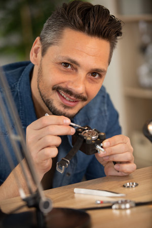 happy watchmaker is repairing the mechanical watches in his workshop