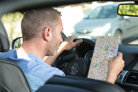 man in car consulting paper roadmap