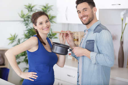 young smiling man feeds his pregnant wife cookies for breakfastの写真素材