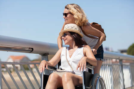 woman pushes friend in wheelchair on the beachの写真素材