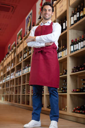 handsome sommelier standing smiling in a wine storeの写真素材