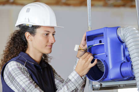 woman builder instaling cooling systemの写真素材