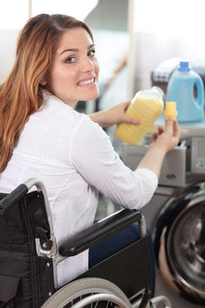 happy disable woman is doing the laundryの写真素材