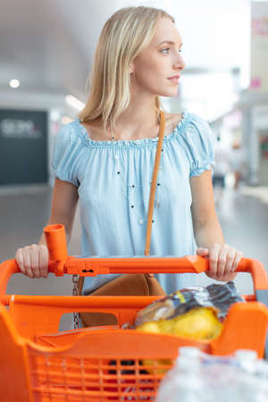 woman with shopping cart trolley outdoor market near car parkingの写真素材