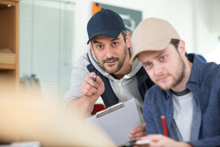 portrait of senior carpenter teaching apprentice