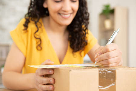 delivery mail shipping smiling woman writing on delivery boxの写真素材