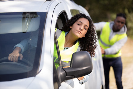 woman steering car being pushed by her partner