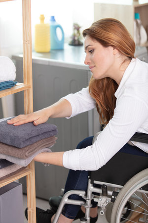 happy young disabled woman in wheelchair doing the laundry