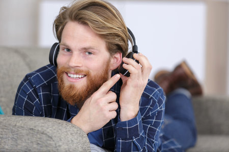 man on couch watches a movie on mobile phone