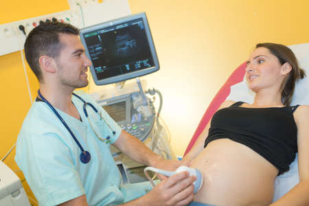 doctor using ultrasound machine on pregnant woman in clinicの写真素材