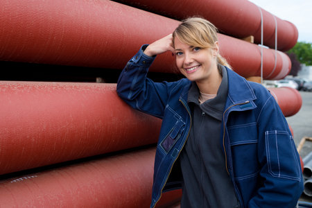 female worker leaning against industrial sized red pipes