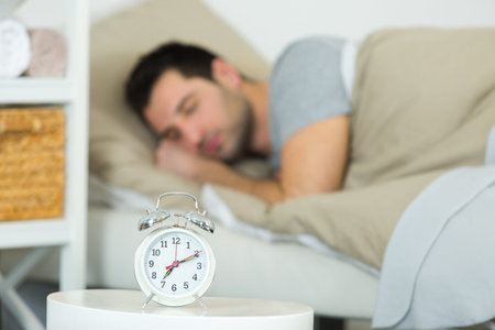 man with alarm clock in bedroom