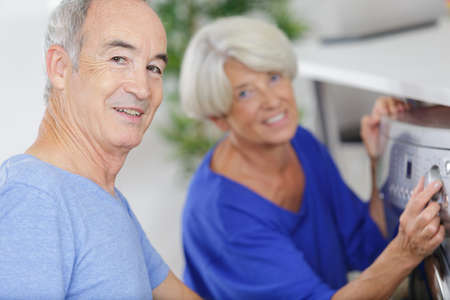 portrait of happy senior couple doing laundryの写真素材
