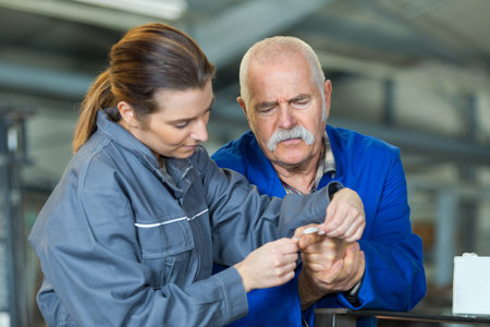 young lady putting plaster on senior mans finger in workplace