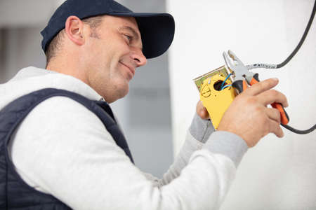 electrician cuts cable at junction-boxの写真素材