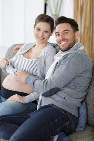 prengant couple holding a tiny pair of baby shoesの写真素材