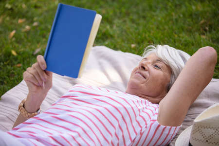 senior woman backyard garden holding a bookの写真素材
