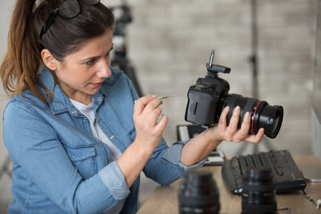 female photographer cleaning dslr fisheye camera lensの写真素材