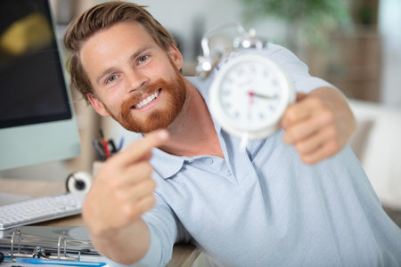 young male contractor repairing alarm clock at workshopの写真素材