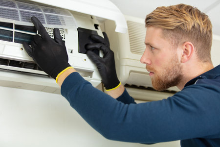 technician repairs wall-mounted air-conditioning unitの写真素材