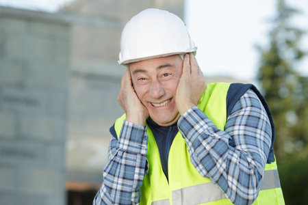 senior builder covering his ears in site