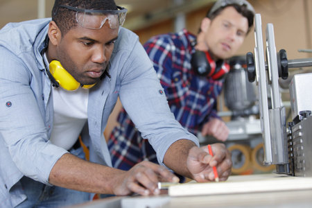 two carpenters measuring wooden board at workshop