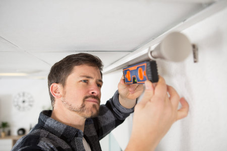 man hanging window curtain indoors