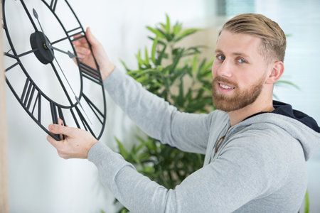 young man installing clock at homeの写真素材