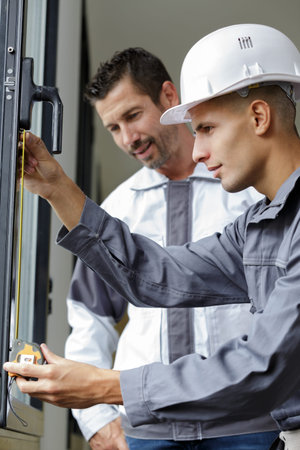 builder measuring a window using a tape measure