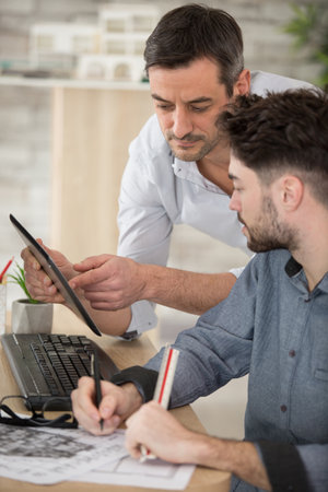 group of two coworkers working with blueprint in officeの写真素材