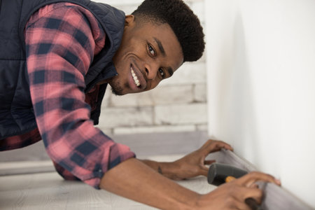 happy male worker installing wooden floorの写真素材